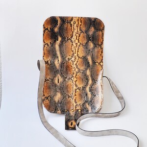 Peut inclure: Un sac &agrave; bandouli&egrave;re en cuir de serpent brun et noir avec une longue bandouli&egrave;re gris clair.