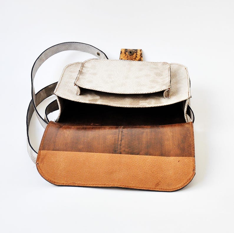 Peut inclure: Un sac &agrave; main en cuir blanc avec un rabat en cuir marron et une petite poche sur le devant. Le sac est ouvert et l'int&eacute;rieur est visible.