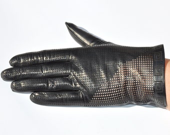 May include: Black leather glove with a perforated design. The glove features a decorative geometric pattern around the wrist. The glove is shown on a white background.