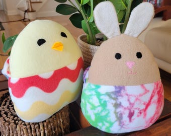 May include: Two plush Easter-themed toys. A yellow chick with red and white stripes and a brown bunny with a tie-dye pattern.