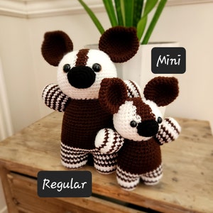 May include: Two crocheted stuffed animals, one brown and white striped and one smaller brown and white striped, with the words "Regular" and "Mini" written on the surface below them.