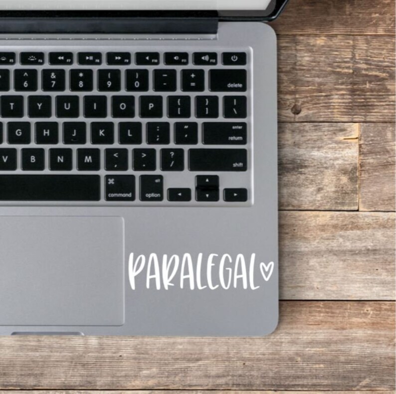 May include: A silver laptop computer with a white sticker on the trackpad that says "PARALEGAL" with a heart symbol.