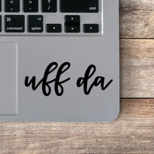 May include: A silver laptop with a black sticker that says "uff da" on the trackpad.