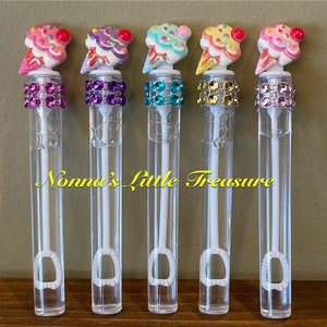 May include: Five clear plastic bubble wands with colorful ice cream cone shaped tops and jeweled rings. The wands have a white bubble wand attached to the bottom.