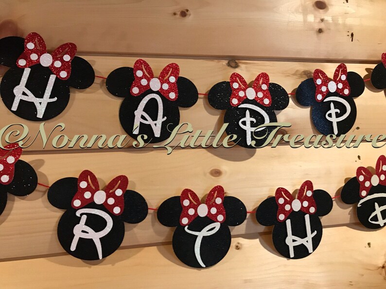 May include: A festive banner with black mouse head shapes, each featuring a white letter spelling "HAPPY BIRTHDAY". Red glitter bows with white polka dots adorn each head. The banner is strung on a red cord.