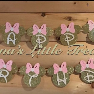 May include: Gold and pink glitter Happy Birthday banner with Minnie Mouse ears and bows. The banner says "Happy Birthday".