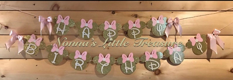 May include: Gold and pink glitter Happy Birthday banner with Minnie Mouse ears and bows. The banner says "Happy Birthday".