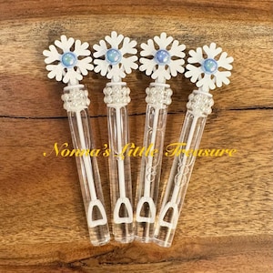 May include: Four white plastic bubble wands with snowflake-shaped tops and blue glitter accents. Each wand has a clear plastic bottle filled with bubble solution and a white plastic wand.