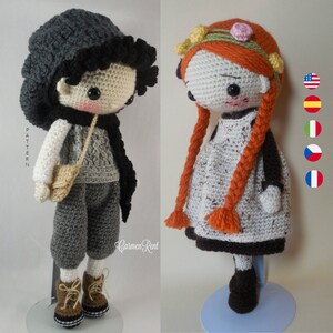 May include: Two crocheted dolls, one with a black hat and gray clothing, the other with a red braid and a white dress. The dolls are standing on a white and blue surface. The word "PATTERN" is visible in the background.