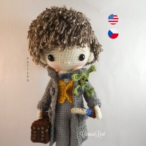 May include: A handmade crochet doll with brown hair, wearing a gray coat, yellow vest, and gray pants. The doll holds a brown satchel and a wand, with a small green creature on its shoulder. The doll is approximately 10 inches tall.