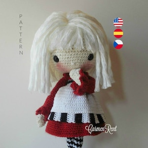 Könnte beinhalten: Häkelpuppe mit weißen Haaren, einem rot-weißen Kleid und schwarz-weißen Strumpfhosen. Die Puppe steht auf einem weißen Ständer. Der Text "Carmen Rent" ist auf dem Kleid der Puppe sichtbar.