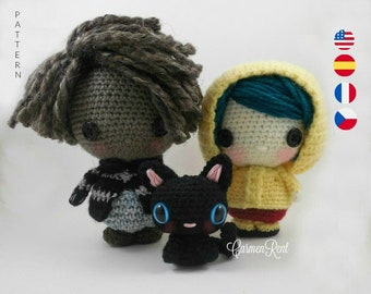 May include: Two crocheted dolls, one with brown hair and a striped sweater, the other with blue hair and a yellow raincoat, stand next to a black crocheted cat.