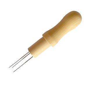 May include: A wooden tool with a handle and three metal needles extending from the end. The tool is used for threading yarn through fabric.
