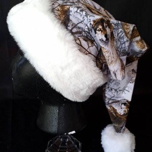 May include: White faux fur trim Santa hat with a wolf print design. The hat has a white pom-pom on the end.