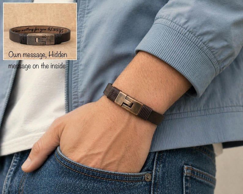 May include: A dark brown leather bracelet with a metal clasp is shown on a person's wrist. The bracelet has a rectangular clasp and a hidden message on the inside. The text on the inside of the bracelet says "these memories for you always".