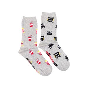 Könnte beinhalten: Ein Paar graue Socken mit einem Film-Motiv. Eine Socke zeigt ein Muster aus Popcorn, Sodagläsern und Filmklappen. Die andere Socke zeigt ein Muster aus Filmkameras, Filmklappen und dem Text "Friday Sock Co."