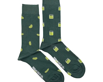 May include: A pair of dark green socks with a pattern of yellow pickles and pickle jars. The socks have the text "FRIDAY SOCK CO." printed on the bottom of the foot.