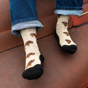 May include: Beige socks with a repeating pattern of brown bear illustrations. The socks have black heels and toes. The person is wearing blue jeans.