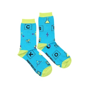 May include: A pair of blue socks with a green cuff. The socks feature a science theme with images of beakers, atoms, and chemical formulas. The text "FRIDAY SOCK CO." is printed on the socks.