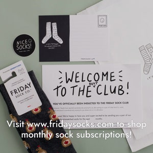 Peut inclure: Une paire de chaussettes grises avec un motif de feuille d'&eacute;rable. Les chaussettes font partie d'un service d'abonnement en bo&icirc;te appel&eacute; "Friday Sock Co.". Le texte "Bienvenue au club !" est &eacute;crit en noir sur fond blanc. Le texte "Vous avez officiellement &eacute;t&eacute; intronis&eacute; au Friday Sock Club" est &eacute;crit en noir sur fond blanc. Le texte "Visitez www.fridaysocks.com pour acheter des abonnements mensuels de chaussettes !" est &eacute;crit en noir sur fond blanc.