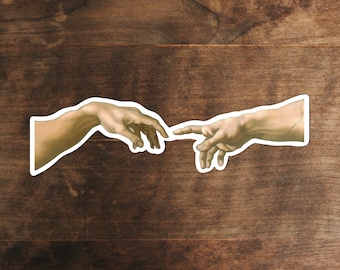 May include: A sticker featuring a close-up of two hands reaching towards each other, inspired by Michelangelo's famous painting "The Creation of Adam".