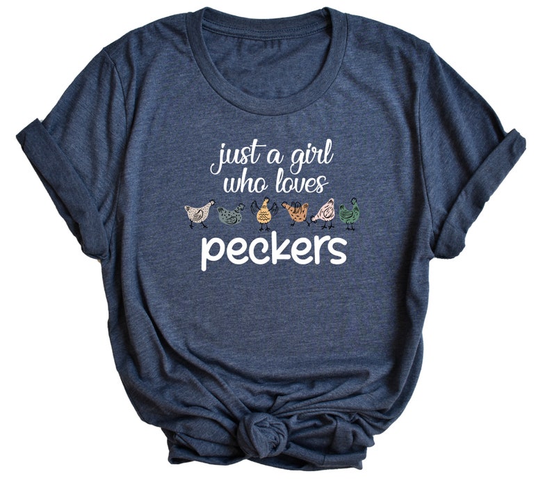 May include: A dark blue t-shirt with the text "just a girl who loves peckers" and a row of colorful cartoon chickens.