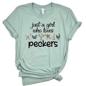 May include: A light blue t-shirt with the text "just a girl who loves peckers" and a line of colorful cartoon chickens.