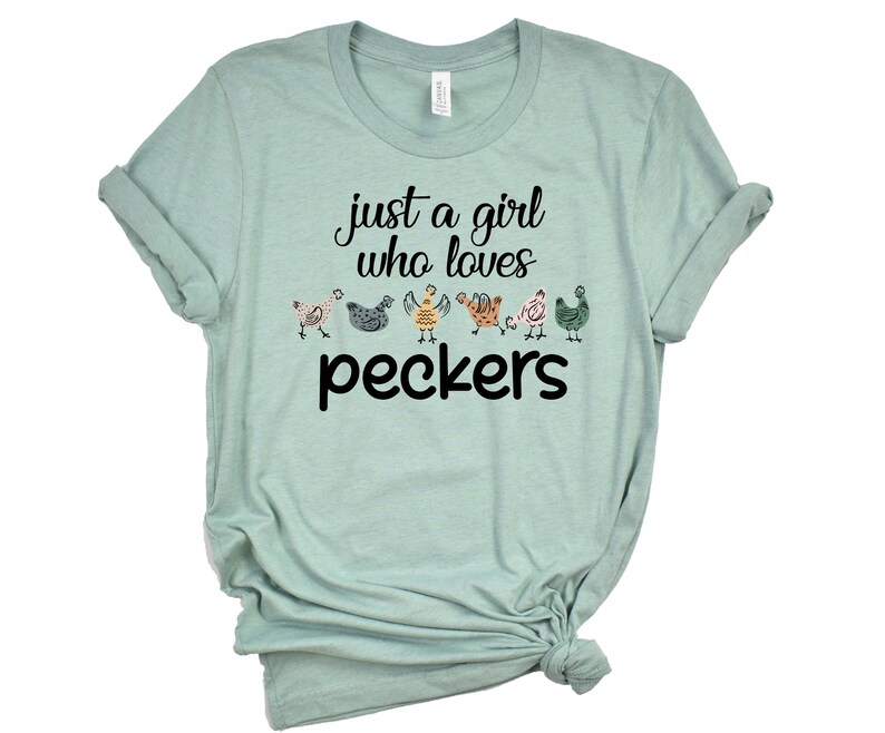 May include: A light blue t-shirt with the text "just a girl who loves peckers" and a line of colorful cartoon chickens.