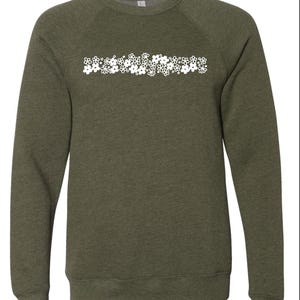 May include: A green sweatshirt with a white floral design across the chest.