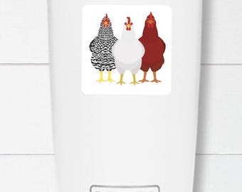 May include: A white Yeti tumbler with a silver rim and base. A square sticker on the front features three cartoon chickens: one black and white, one white, and one red, all with yellow feet and red combs.