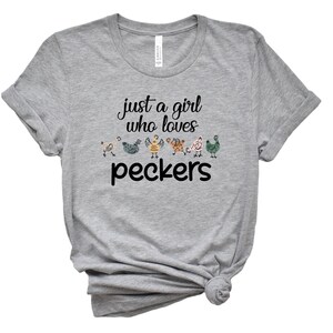 May include: Gray t-shirt with the text "just a girl who loves peckers" and a line of colorful cartoon chickens.