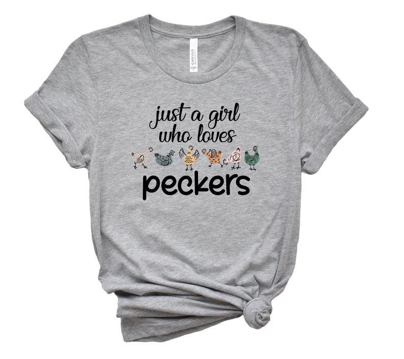May include: Gray t-shirt with the text "just a girl who loves peckers" and a line of colorful cartoon chickens.