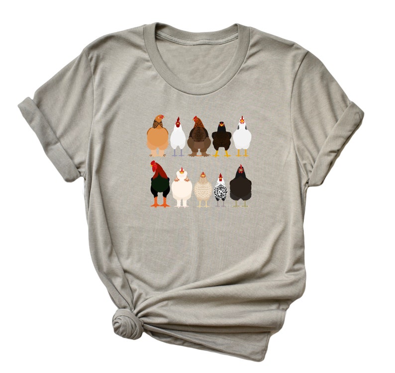 May include: A light grey t-shirt featuring a graphic of a line of chickens in various colours and breeds. The chickens are all facing forward with their wings tucked in.