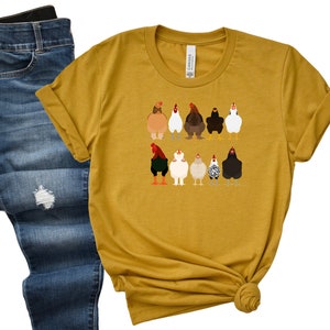 May include: A mustard yellow t-shirt featuring a graphic of a line of chickens in various colours and patterns.
