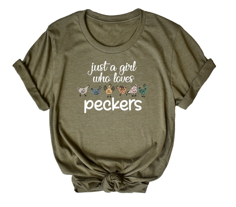 May include: A green t-shirt with the text "Just a girl who loves peckers" and a row of colorful chickens printed on the front.