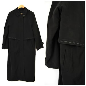 May include: A long black wool coat with a single button closure and a stitched detail around the pockets and collar.