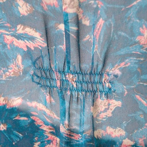 K&ouml;nnte beinhalten: Nahaufnahme eines blauen und rosafarbenen Blumenstoffes mit einer Reihe von N&auml;hten in der Mitte.