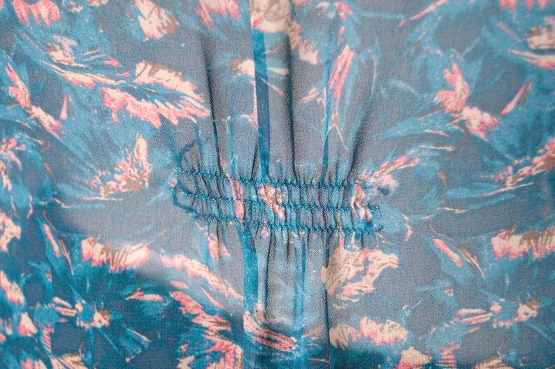 K&ouml;nnte beinhalten: Nahaufnahme eines blauen und rosafarbenen Blumenstoffes mit einer Reihe von N&auml;hten in der Mitte.
