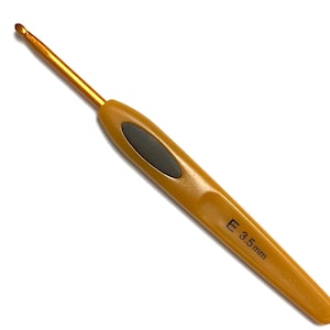 May include: A gold crochet hook with a black grip and the size "E 3.5 mm" printed on the handle.