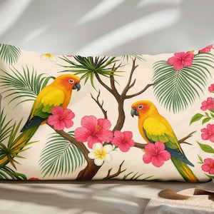 May include: Rectangular decorative pillow featuring a tropical design. Two yellow and orange parrots perch on a tree branch with pink hibiscus flowers and green palm leaves against a cream background. The pillow is a decorative home accent.