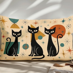 May include: A rectangular cushion with a mid-century modern design. The cushion has a cream background with three black cat illustrations. The design includes starbursts, circles, and geometric shapes in orange, teal, and gold.