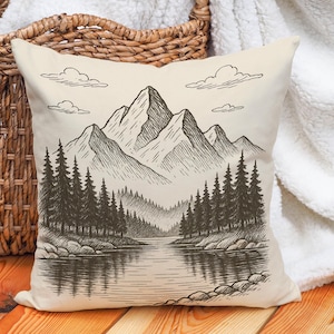 May include: Square throw pillow with a black and white mountain and lake landscape design. The pillow features a detailed pen and ink style illustration of a mountain range, trees, and a body of water.