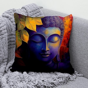 Könnte beinhalten: Ein quadratisches Zierkissen mit einem lebendigen künstlerischen Druck eines Buddha-Gesichts in tiefen Blau- und Violetttönen. Das Design zeigt leuchtend gelbe und orangefarbene Blätter auf der linken Seite und einen warmen, feurigen Hintergrund.