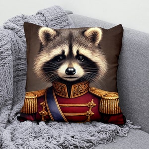 Peut inclure: Un coussin décoratif avec une illustration colorée d'un raton laveur portant un uniforme militaire rouge et or. Le raton laveur a une expression sérieuse et regarde directement le spectateur.