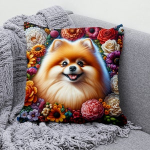 May include: A fluffy orange Pomeranian dog with a happy expression is surrounded by a colourful wreath of flowers. The flowers are in shades of red, pink, yellow, orange, and purple.