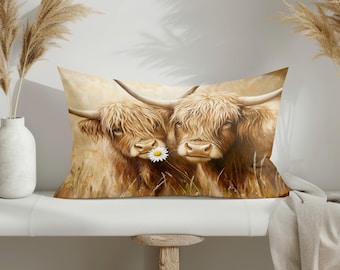 May include: Rectangular pillow featuring a watercolor painting of two Highland cows. The cows have long, shaggy, light brown fur and large horns. One cow holds a daisy in its mouth. The background is a field of tall grass.