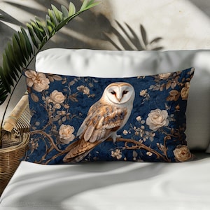 May include: A blue and white throw pillow with a white barn owl perched on a branch with floral accents. The owl has brown and white feathers and yellow eyes.