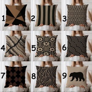 Könnte beinhalten: Neun dekorative Zierkissen mit verschiedenen geometrischen und von der Natur inspirierten Designs. Kissen mit Mustern wie Dreiecken, Streifen, Wellen, Blumen und einer Bärensilhouette. Farben sind Schwarz, Braun und Beige und bieten eine Reihe von Stilen für die Inneneinrichtung.