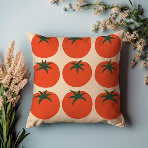 May include: Square throw pillow with a repeating pattern of bright red tomatoes with green stems on a cream background. The pillow is a decorative item, perfect for adding a pop of color to any room. The pillow is a square shape.