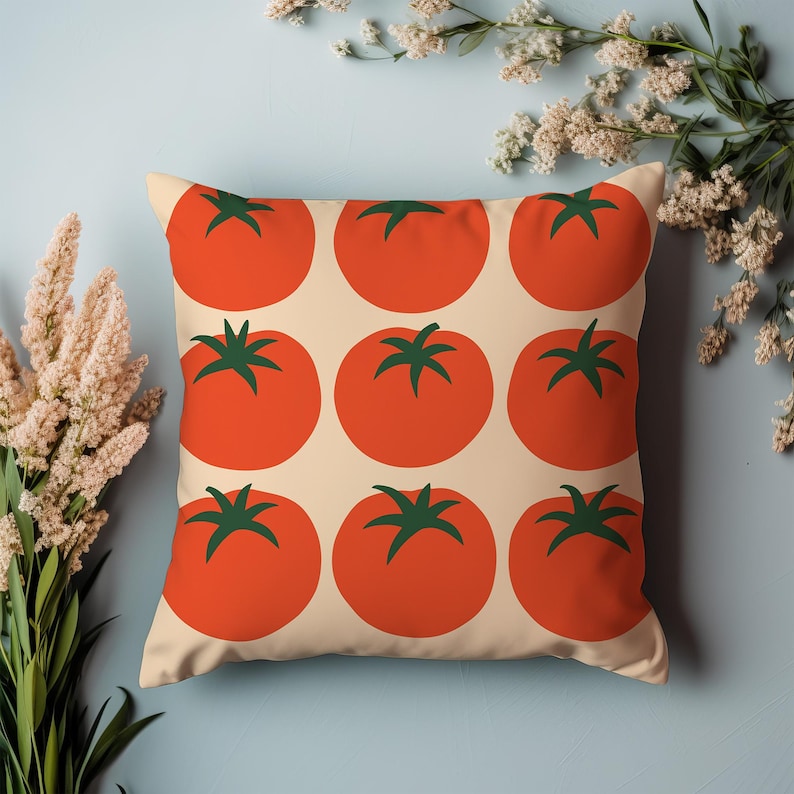 May include: Square throw pillow with a repeating pattern of bright red tomatoes with green stems on a cream background. The pillow is a decorative item, perfect for adding a pop of color to any room. The pillow is a square shape.